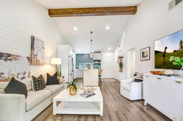 living area with beam ceiling, visible vents, light wood-style flooring, and high vaulted ceiling