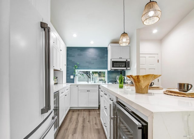 kitchen with light stone counters, a center island, freestanding refrigerator, light wood-style floors, and decorative backsplash