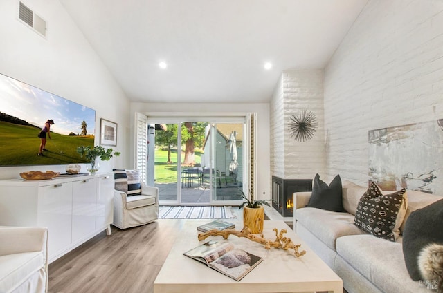 living area featuring visible vents, a multi sided fireplace, light wood-type flooring, recessed lighting, and high vaulted ceiling