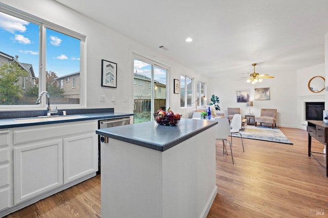 kitchen with sink, white cabinets, a kitchen island, and light hardwood / wood-style flooring