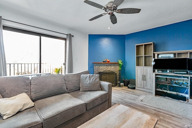 living room with ceiling fan, light hardwood / wood-style floors, and a textured ceiling