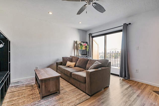 living room with ceiling fan, a textured ceiling, and light wood-type flooring