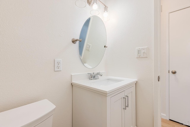 bathroom with hardwood / wood-style flooring, vanity, and toilet