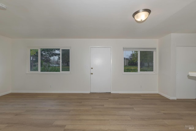 empty room featuring a healthy amount of sunlight and light hardwood / wood-style floors