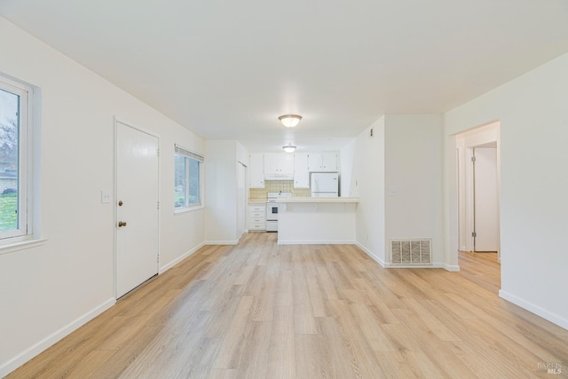 unfurnished living room featuring light wood-type flooring and a healthy amount of sunlight