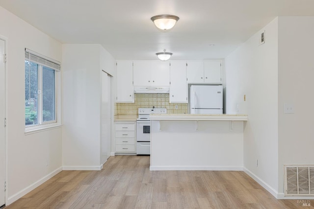 kitchen with stove, premium range hood, white refrigerator, light hardwood / wood-style floors, and white cabinetry