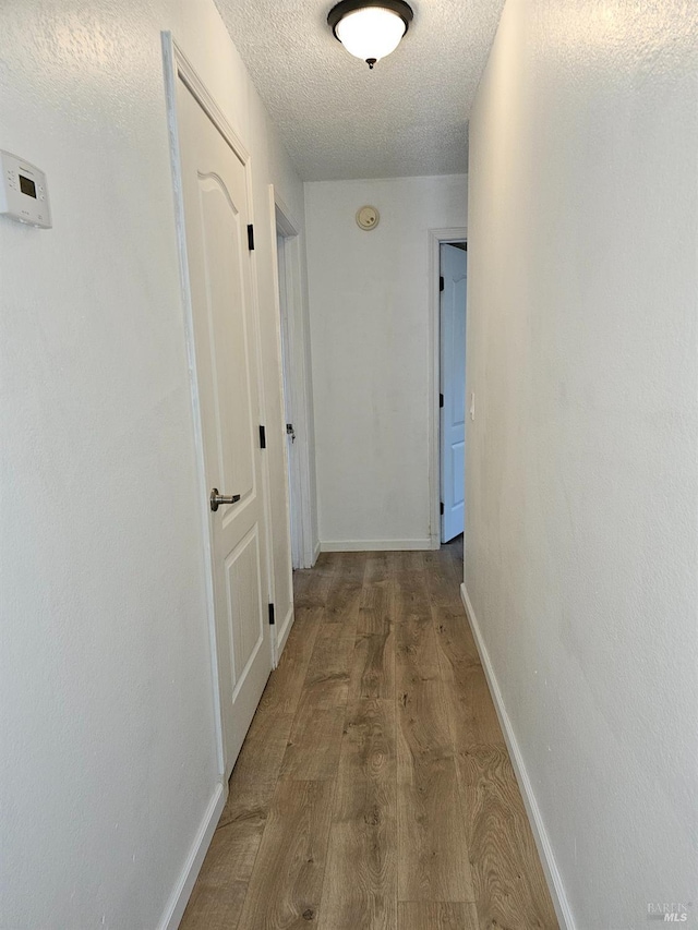 hall featuring light hardwood / wood-style floors and a textured ceiling