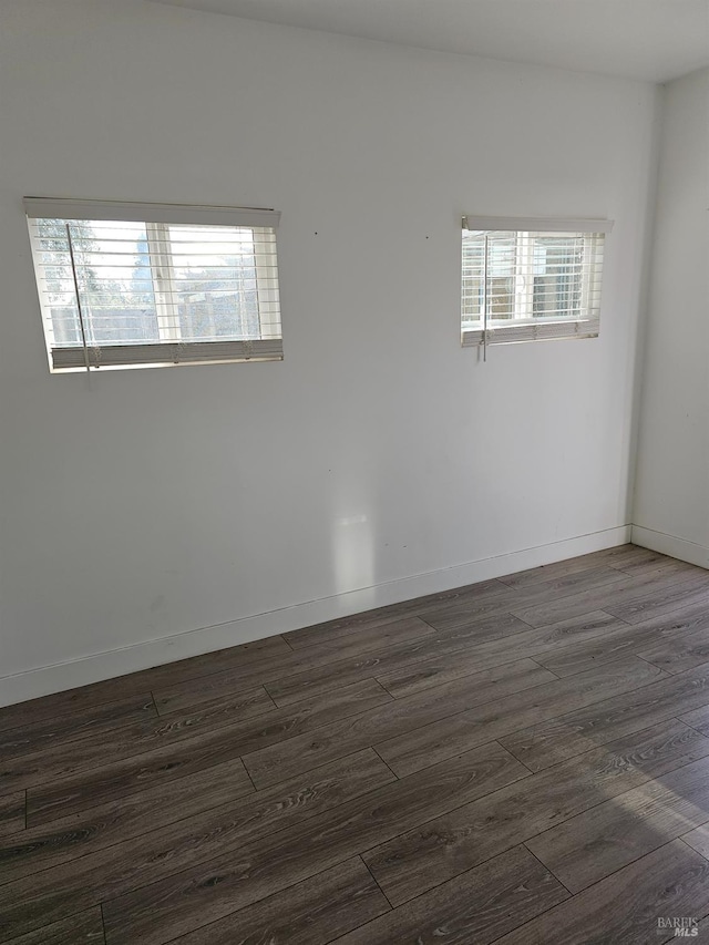 empty room featuring dark wood-type flooring and a healthy amount of sunlight