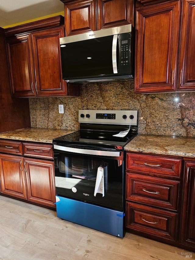 kitchen with tasteful backsplash, light stone counters, and appliances with stainless steel finishes