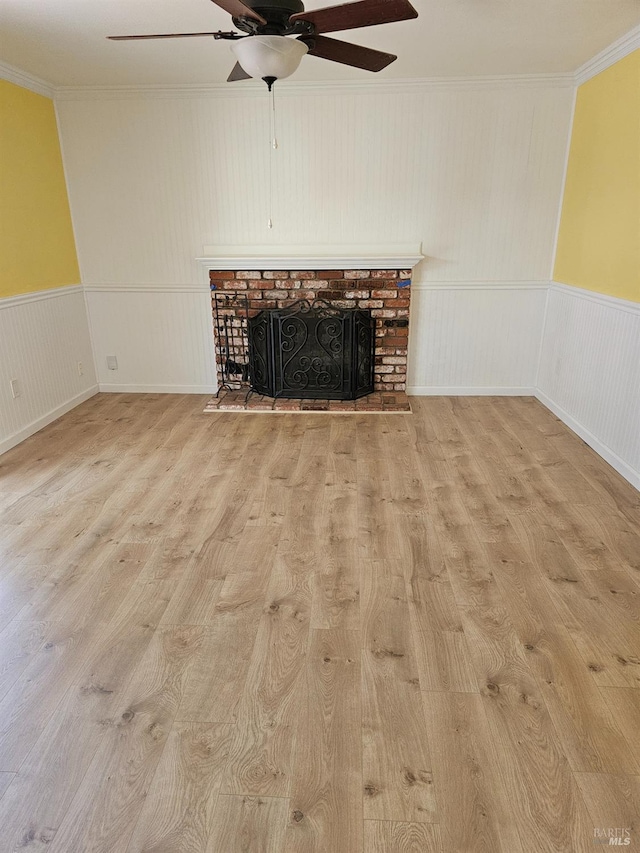 unfurnished living room with crown molding, a fireplace, ceiling fan, and light hardwood / wood-style floors