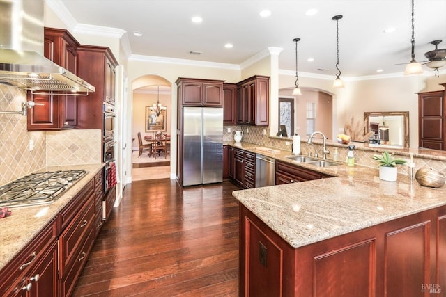 kitchen featuring sink, stainless steel appliances, wall chimney range hood, dark hardwood / wood-style floors, and decorative light fixtures