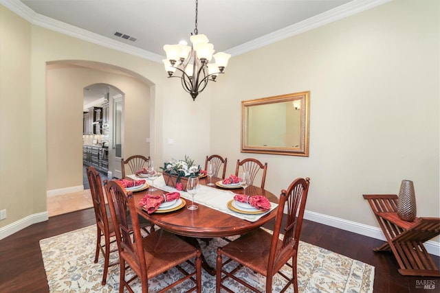 dining room featuring ornamental molding, dark wood-type flooring, and an inviting chandelier