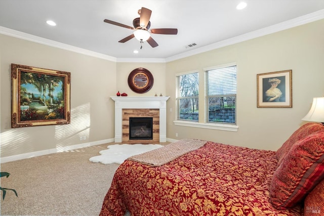 bedroom featuring carpet, ceiling fan, crown molding, and a tiled fireplace