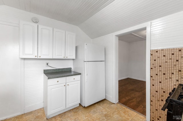 kitchen with vaulted ceiling, white fridge, and white cabinets