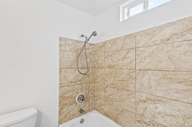 bathroom featuring tiled shower / bath and toilet