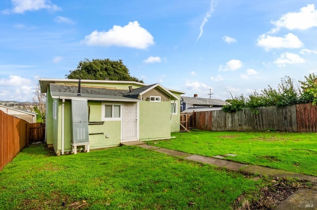 rear view of property featuring an outdoor structure and a lawn