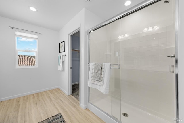 full bathroom featuring wood finished floors, baseboards, recessed lighting, a stall shower, and a walk in closet