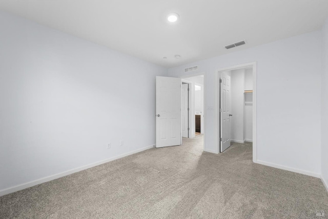 unfurnished bedroom with a spacious closet, baseboards, visible vents, and carpet floors