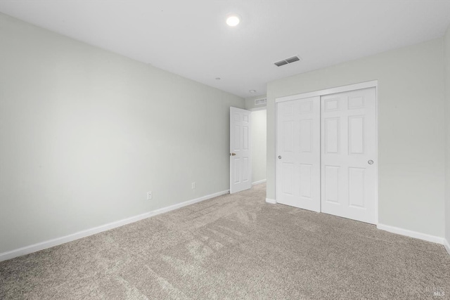 unfurnished bedroom with carpet, visible vents, a closet, and baseboards