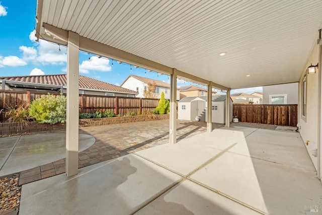 view of patio featuring a storage unit, a fenced backyard, and an outdoor structure