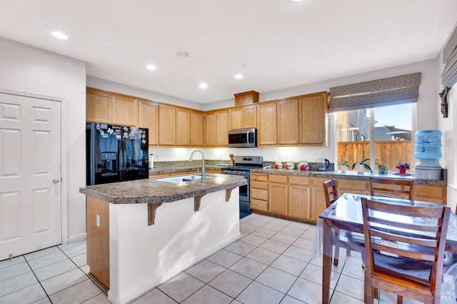 kitchen featuring a kitchen breakfast bar, stainless steel appliances, light tile patterned floors, sink, and a kitchen island with sink