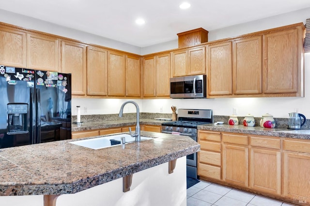 kitchen featuring appliances with stainless steel finishes, sink, light tile patterned floors, a kitchen breakfast bar, and an island with sink