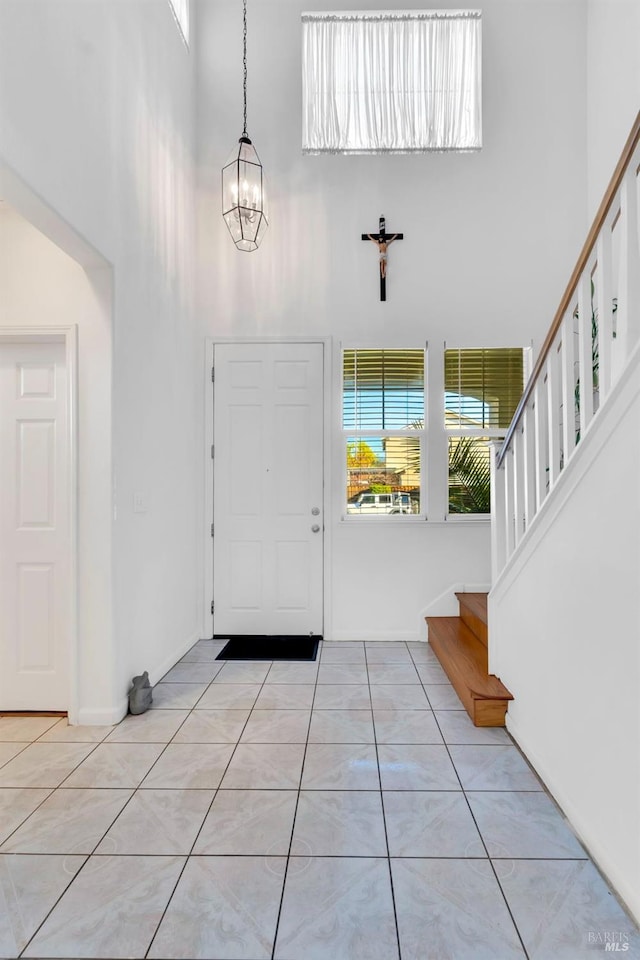 tiled foyer with a towering ceiling and a chandelier