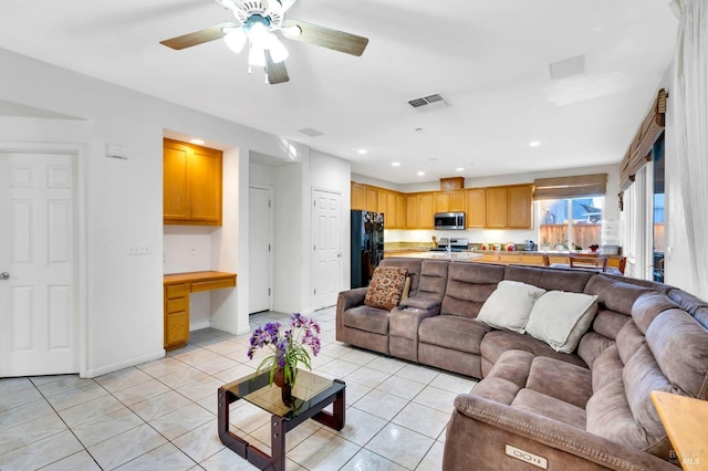 living room with light tile patterned flooring, ceiling fan, and built in desk