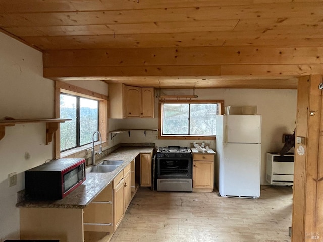 kitchen featuring sink, light hardwood / wood-style flooring, dark stone countertops, white fridge, and gas stove