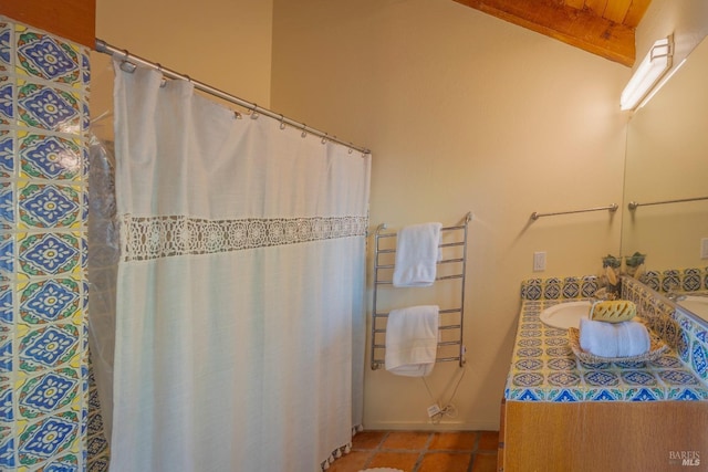 bathroom featuring tile patterned floors, vanity, and vaulted ceiling