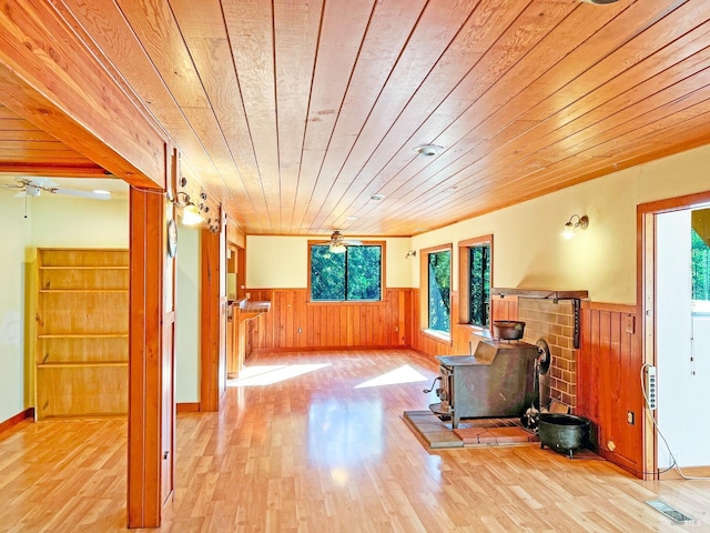 interior space featuring wood walls, a wood stove, light hardwood / wood-style flooring, and wooden ceiling