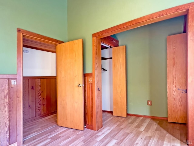 unfurnished bedroom with wood walls and light hardwood / wood-style flooring