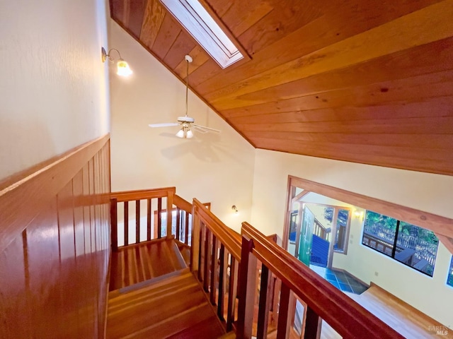 stairway with vaulted ceiling with skylight, ceiling fan, wooden ceiling, and hardwood / wood-style flooring