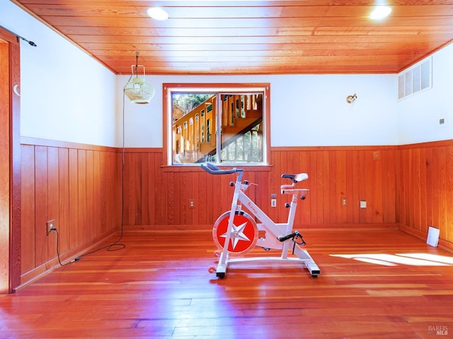 workout area featuring crown molding, wooden walls, hardwood / wood-style floors, and wooden ceiling