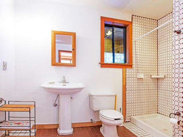 bathroom featuring tile patterned flooring, toilet, and a tile shower