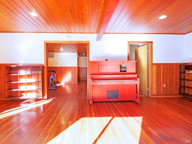 interior space with beam ceiling, wood walls, hardwood / wood-style floors, and wooden ceiling