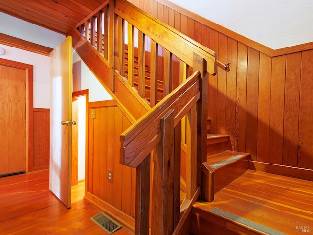 staircase with wood walls and wood-type flooring