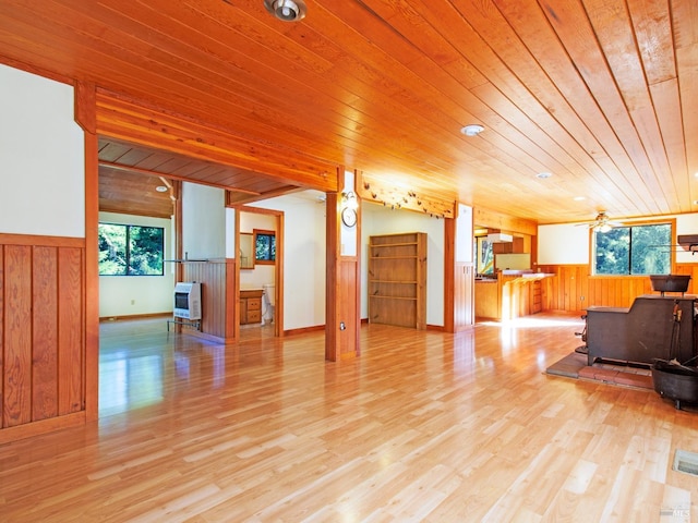 living room featuring wood walls, a wood stove, wooden ceiling, ceiling fan, and light wood-type flooring