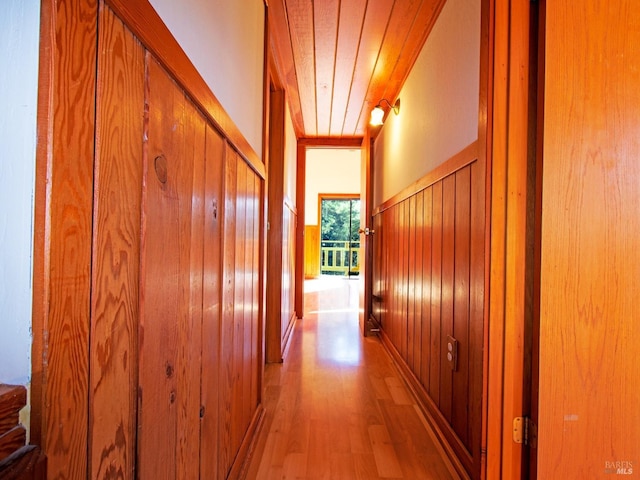 hallway with hardwood / wood-style flooring, wood walls, and wood ceiling