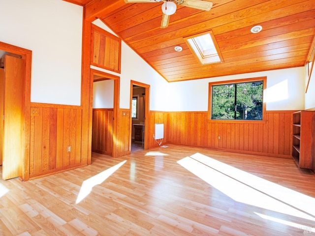 interior space featuring light wood-type flooring, vaulted ceiling with skylight, wood ceiling, ceiling fan, and wood walls