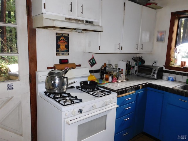 kitchen featuring blue cabinetry, tile countertops, white gas range, and a healthy amount of sunlight