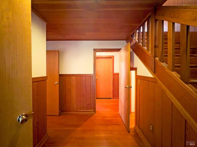 hallway featuring light hardwood / wood-style flooring, wooden walls, and wood ceiling