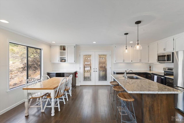 kitchen featuring a kitchen island with sink, white cabinets, sink, light stone countertops, and stainless steel appliances