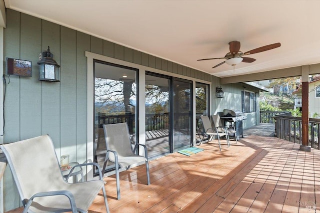 wooden terrace featuring ceiling fan and a grill