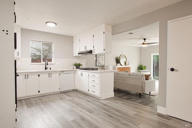 kitchen with stainless steel gas stovetop, white cabinets, white dishwasher, a sink, and under cabinet range hood