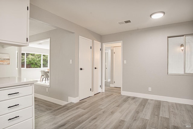 unfurnished room featuring light wood-style floors, baseboards, and visible vents