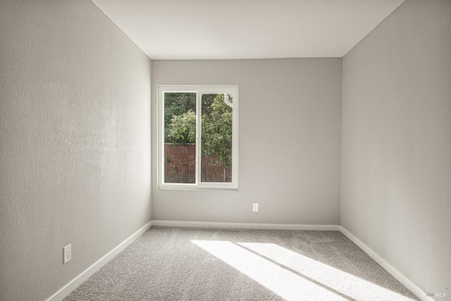 carpeted spare room featuring baseboards