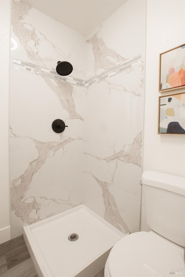 bathroom with a marble finish shower and toilet