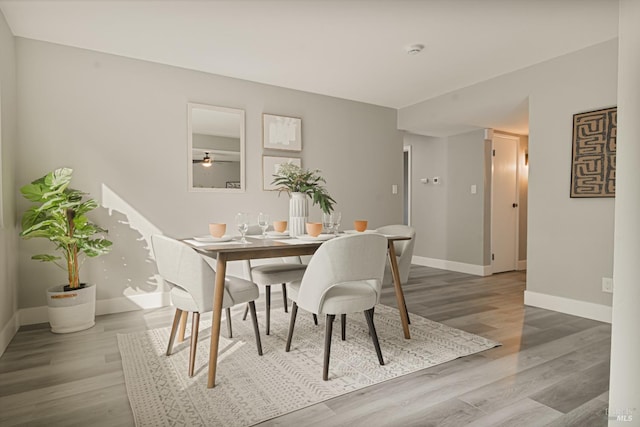 dining space with baseboards and wood finished floors