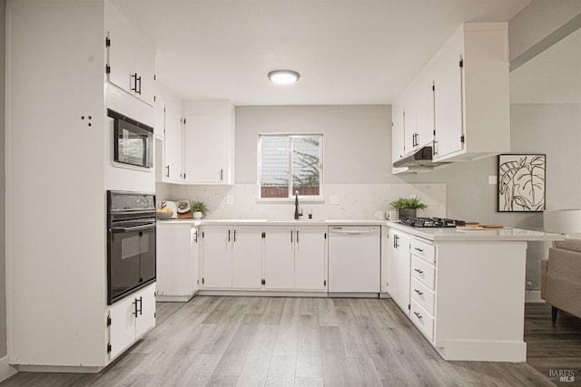 kitchen featuring black appliances, a sink, light countertops, and white cabinets